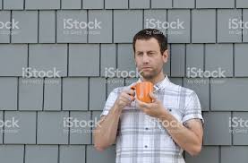 Man Holding An Orange Coffee Cup With Two Hands With A Gray ...